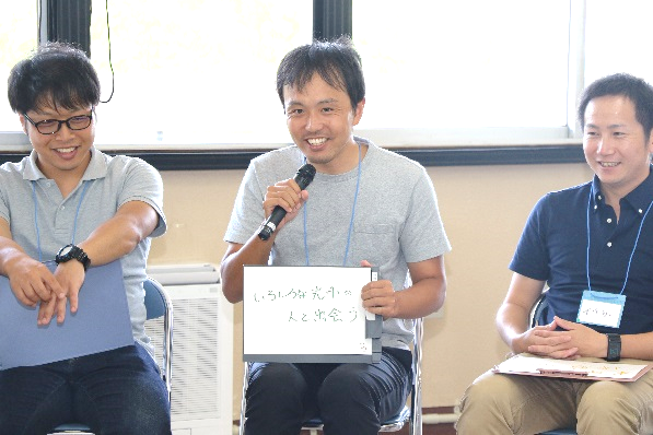 座ってマイクを持って話す男性と座って聞く男性二人の写真