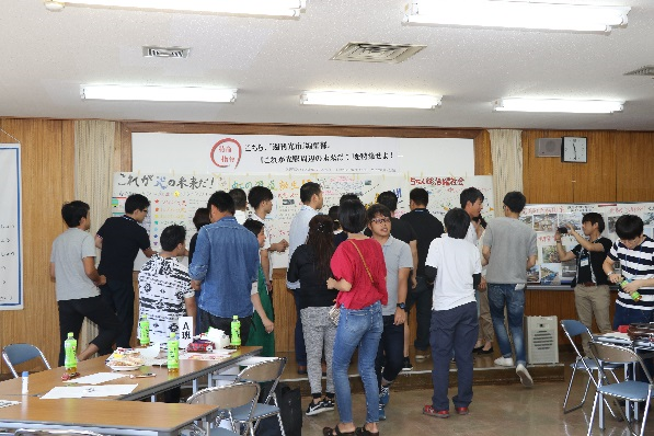 室内で前に貼られたパネルを見る若者たちの写真
