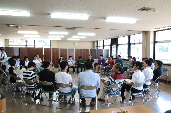 室内で輪になって座る若者たちの写真