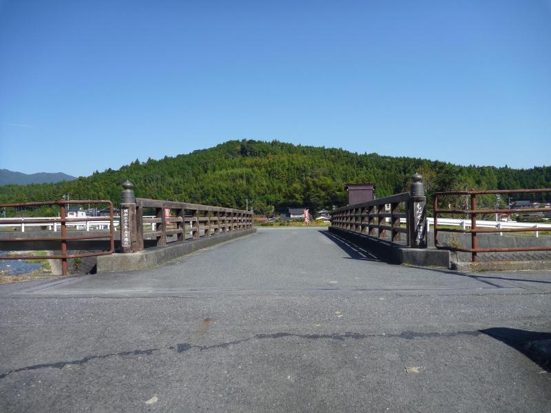 昼間に川にかかった橋を道路上から撮った写真