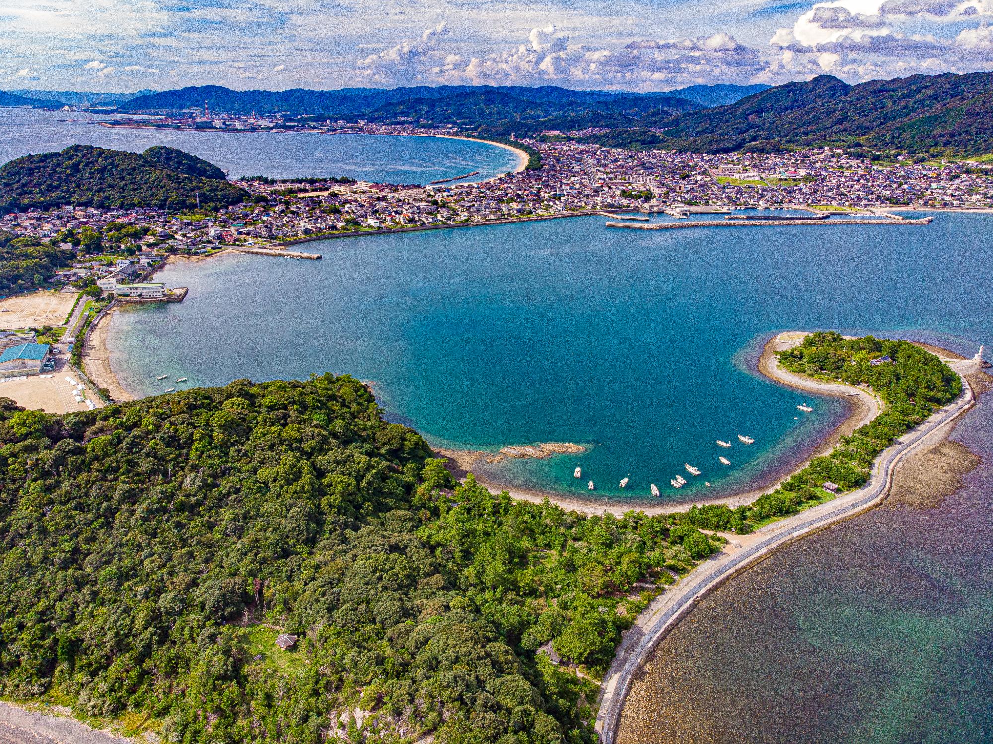 青い海に突き出た岬にそびえ立つ山々の写真