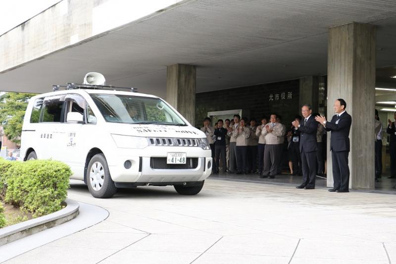 職員派遣の車は会社の前に止まっています。皆さんが拍手をしている写真