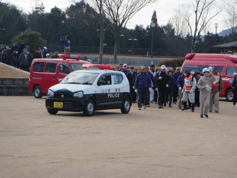 パトカーとその奥に防災訓練に集まった人々の写真