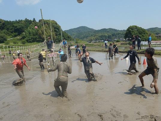 田んぼのコートの中でどろんこになりながらバレーの試合をしている写真