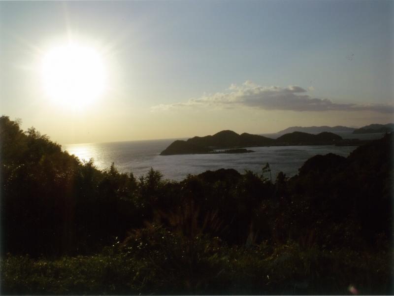 海の向こうに輝く太陽と海に浮かぶ島の写真