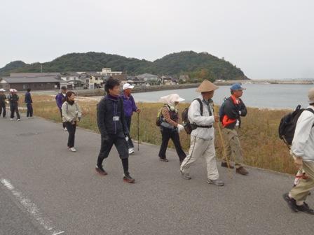 海岸沿いを杖を突いて歩く大勢の参加者の写真
