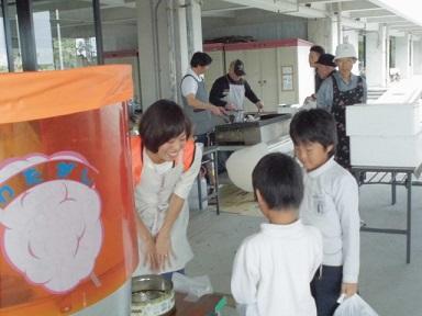 綿菓子の販売ブースで女性隊員が子供らに綿菓子を販売している写真