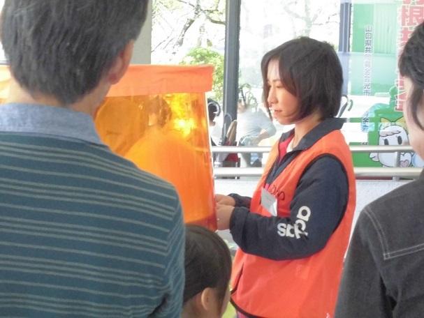 女性隊員が綿菓子を作っているのを待っている人々の写真