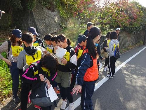 車が通る道沿いで道路の端に集まって車が通過するのを待っている参加者達の写真
