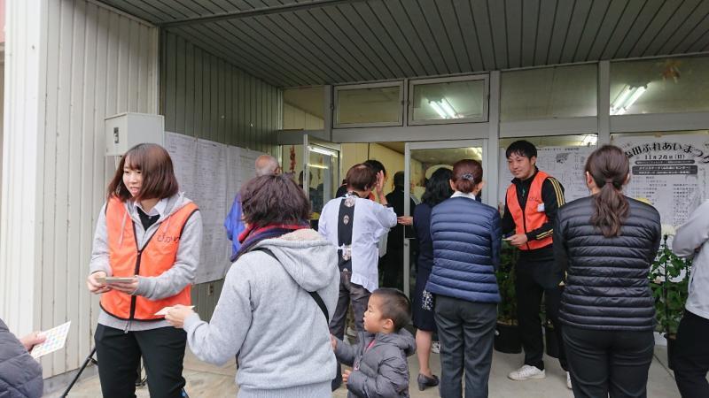 オレンジ色のベストを着た関係者が、市民にビンゴカードを配っている写真