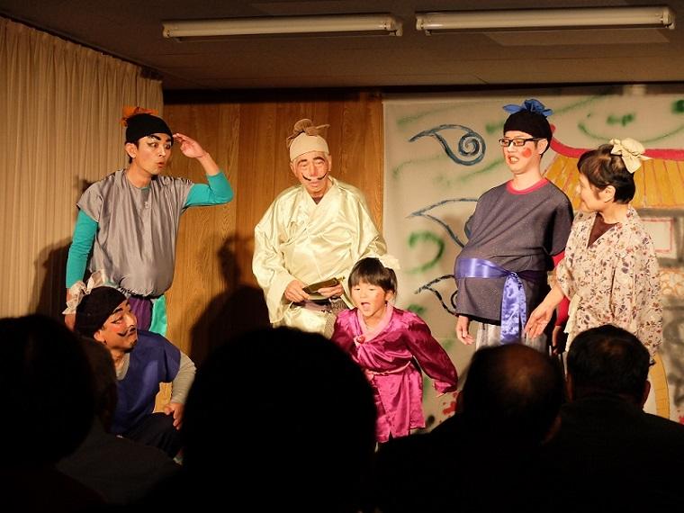 それぞれの役のメイクと衣装を着て舞台上で演劇を披露している和楽輪楽一座の写真