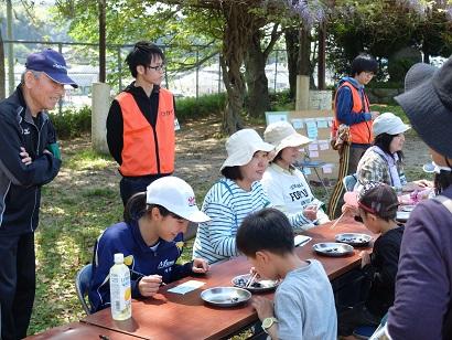 参加者の親子の方が食事している様子を隊員の人達が見守っている写真