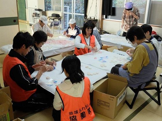 ついた餅をテーブルの上で丸めて箱詰めしている地域ふれあい協働隊と伊保木文化祭スタッフの写真