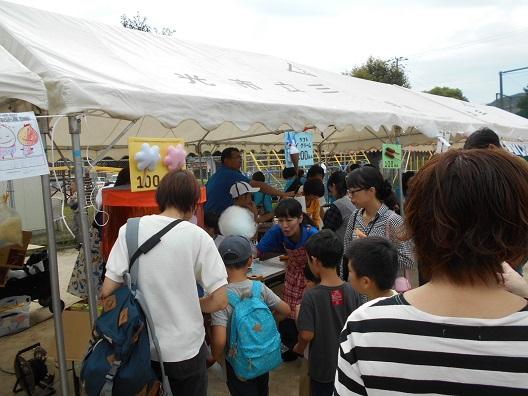 テントの前にたくさんの参加者が集まっており、中で販売されている綿菓子を買っている男の子の写真