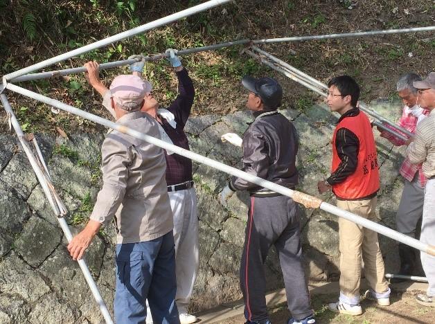 6人の男性がテントの骨組みを組み立てている写真