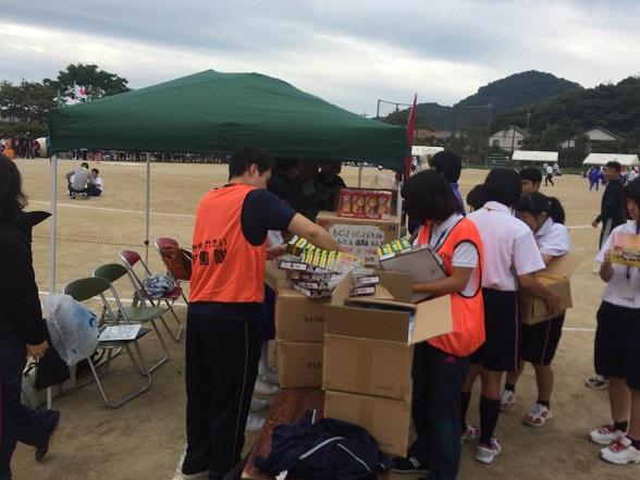 段ボールから景品を取り出している隊員と景品を受け取っているブラウスにジャージ姿の学生たちの写真