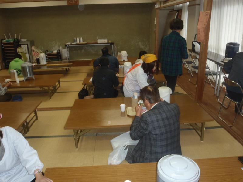 室内に用意された机で、食事をする男女の写真