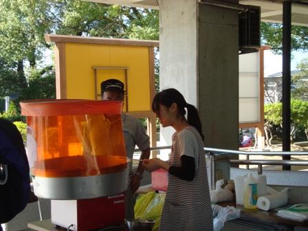 綿菓子を作る機械の横に、男性1人と女性1人が立っている写真