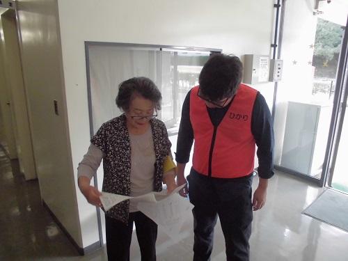 年配の女性が資料を手に持っており、隊員の男性と資料を見ながら確認をしている写真