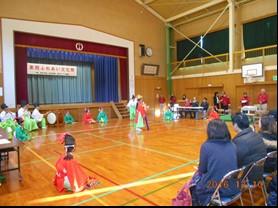 体育館にて袴姿に烏帽子を付けた人々が剣詩舞や演奏を行っている写真