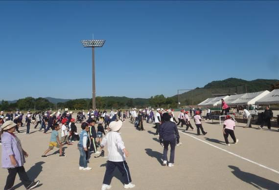 秋晴れの下、体育大会で運動場の中央に移動しようとしている参加者の写真