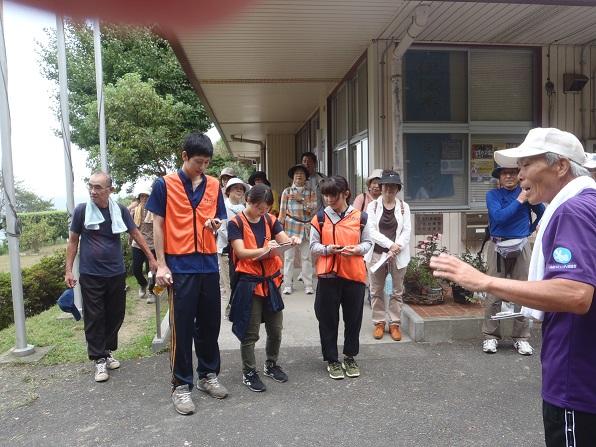 ゴール地点でストップウォッチを持って読み上げる男性隊員とファイルの上に記録している女性隊員の様子を参加者が見ている写真