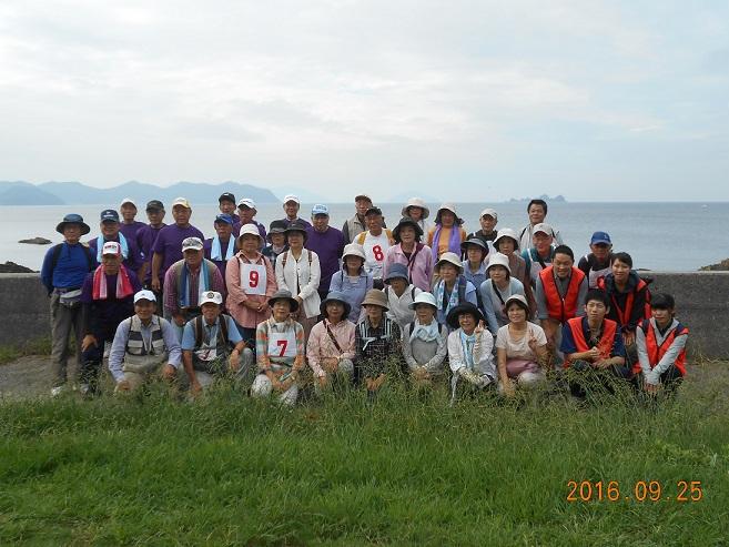 海沿いでウォークラリーの参加者と隊員の方々が記念撮影している写真