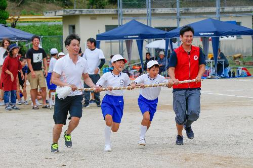 地元小学校の運動会に参加し、児童と棒を持って走る競技に参加する川口隊員