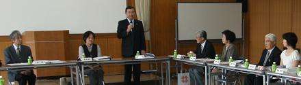 机を前にして並んで座る参加者たちと、マイクを持って発言する参加者の写真