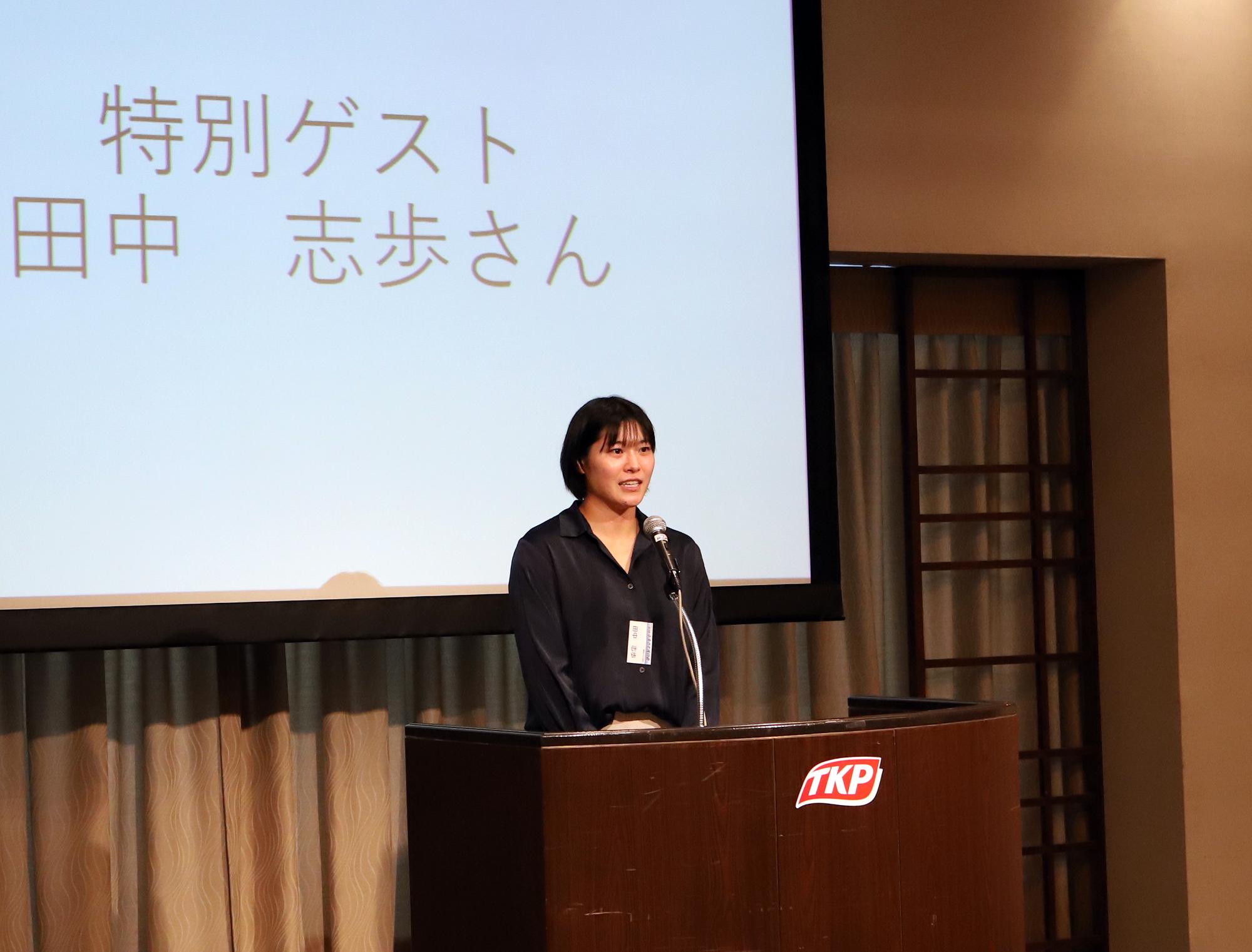 マイクの前で挨拶する女性