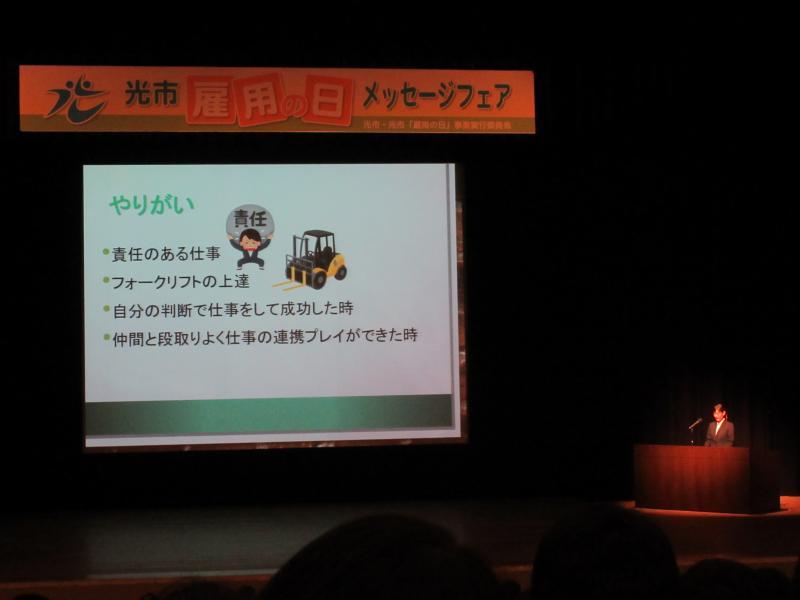 ステージ上のスクリーンに「やりがい」と書かれたスライドが映し出されている写真