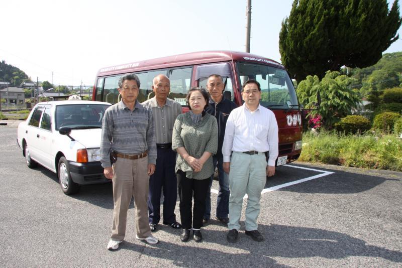 バスとタクシーの前で撮られた有限会社大和タクシーの従業員の集合写真