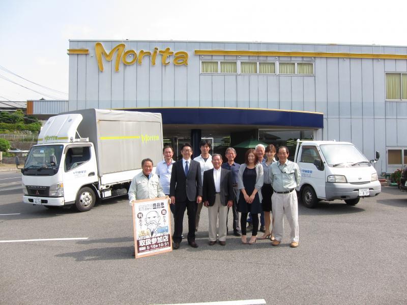 「Morita」と書かれた建物の前で撮られた株式会社守田家具の従業員の集合写真