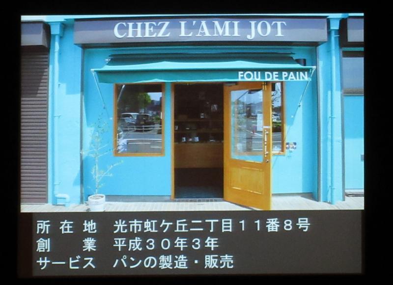 水色に茶色いドアがある店舗外観の写真