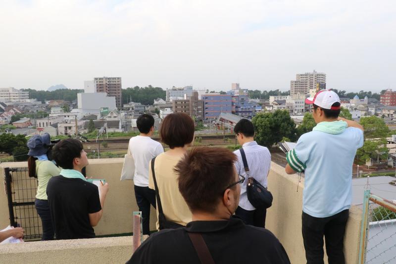 昼間に屋上から街を眺める若者たちの写真