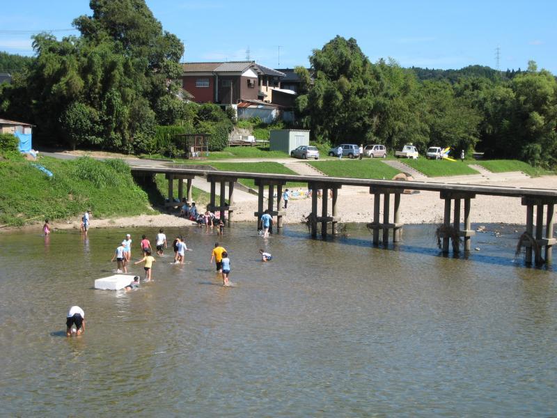 橋の側の浅い川で子供が遊んでいる写真