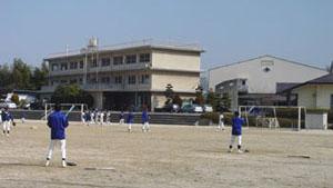グラウンドで活動する生徒と光市立島田中学校外観の写真