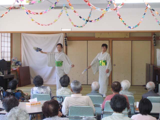 畳の部屋で白い着物を着て踊りを披露する人の写真