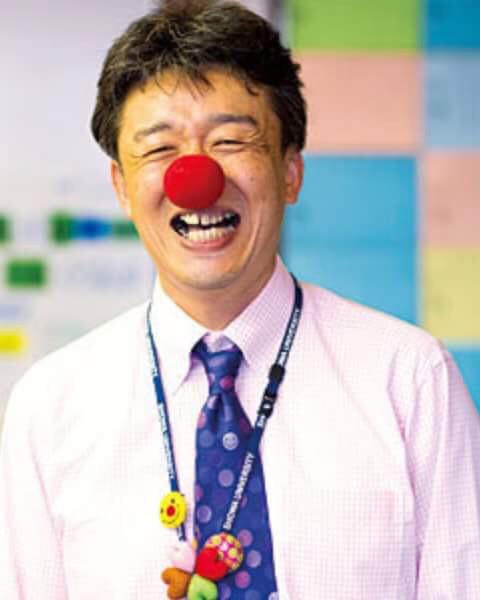 ワイシャツ姿に赤鼻を付け、満面の笑みを浮かべる副島氏の写真