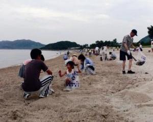 海岸で親子が清掃活動している写真