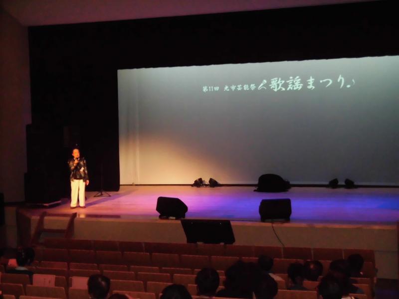 舞台の左端で歌っている中年男性の写真