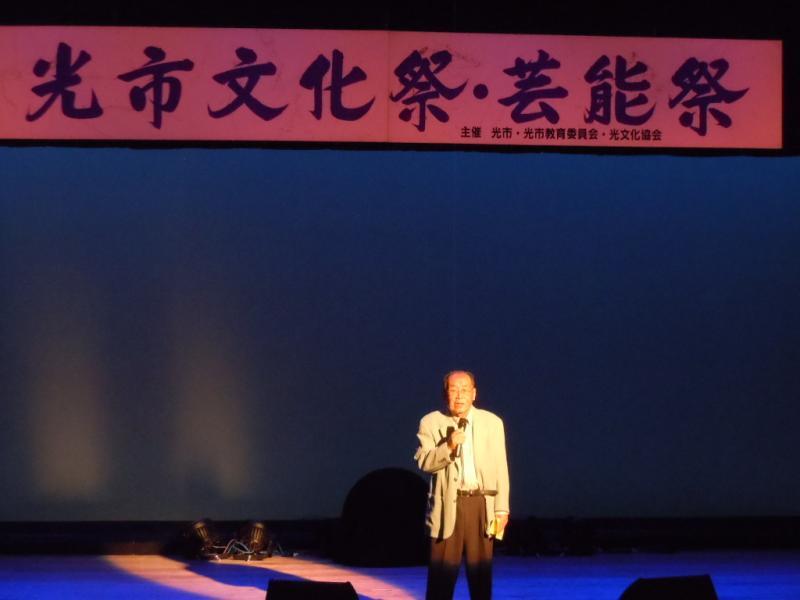 光市文化祭・芸能祭の横断幕のある舞台の上で歌う男性の写真