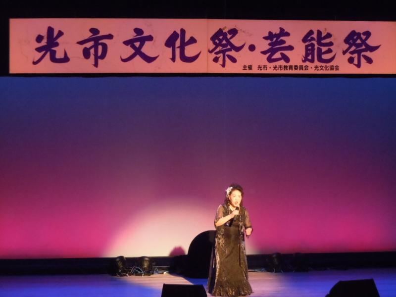 光市文化祭・芸能祭の横断幕のある舞台の上で歌う女性の写真