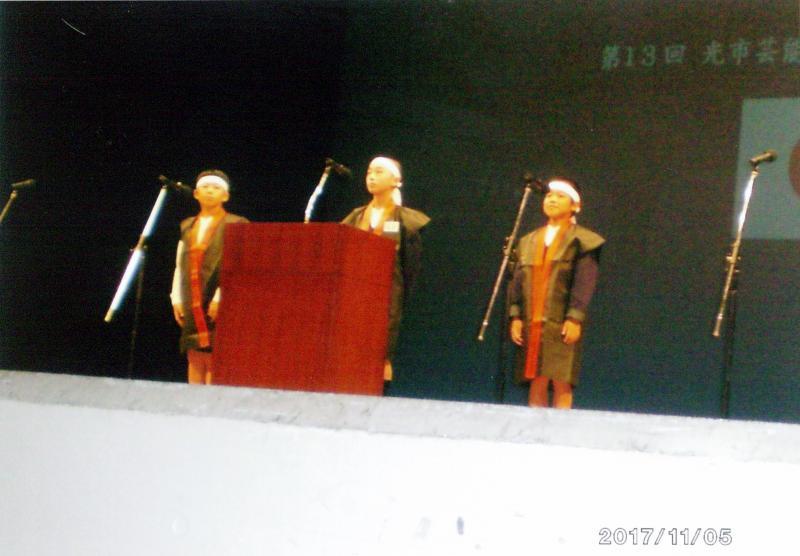 舞台上でおそろいの和装で吟詠する3人の少年の写真