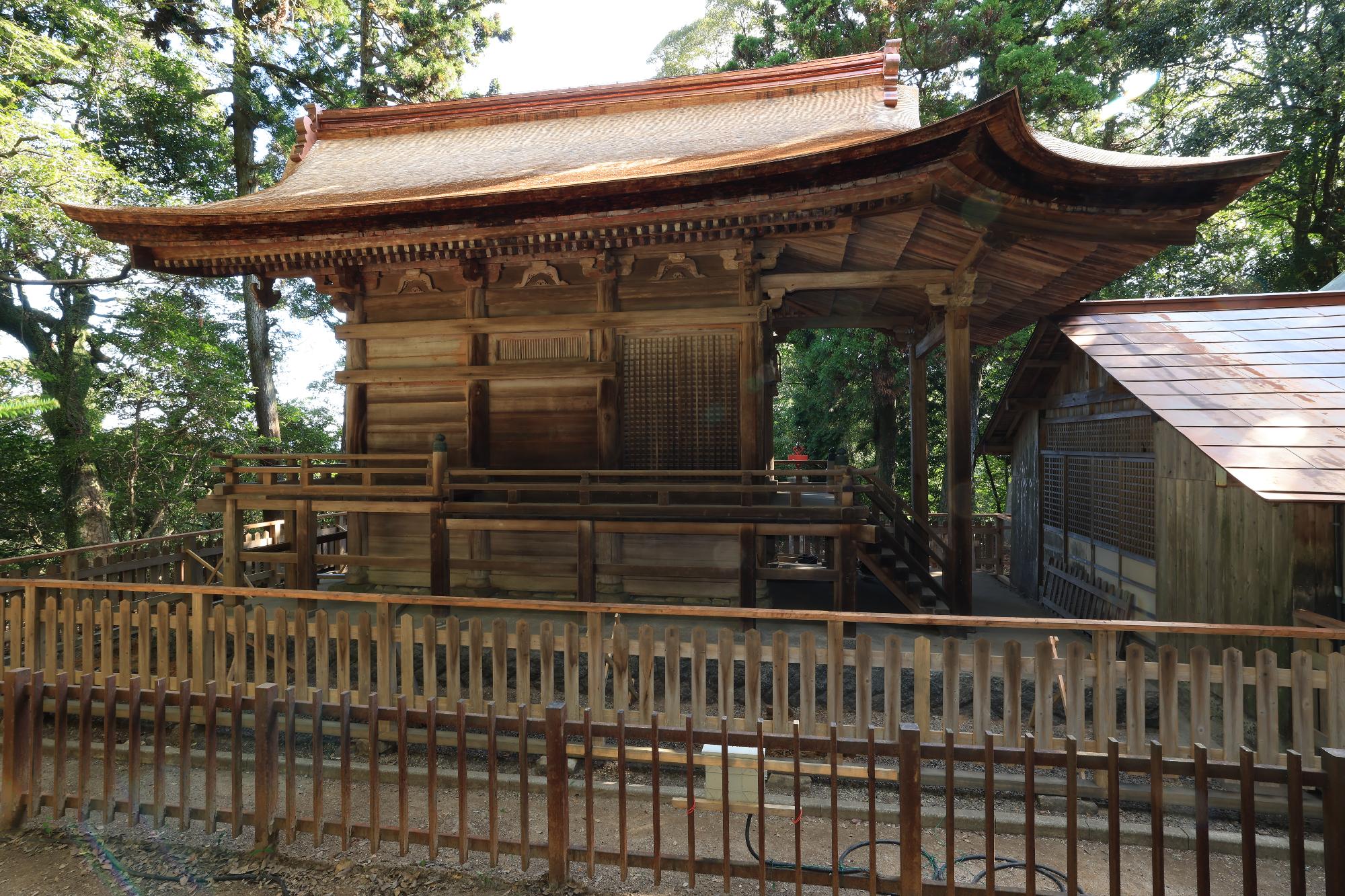 柵の向こうに建っている木造の石城神社本殿の写真
