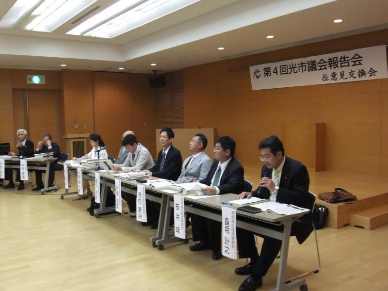 第4回光市議会報告会で会議テーブルに一列に座る議員たち9名の写真