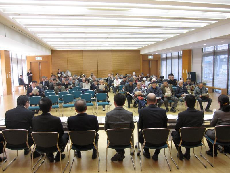 報告会会場にて座席に座る議員の後ろ姿と参加者たちの写真