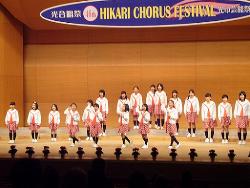 光市民ホールにて光市合唱連盟加盟団体が合唱を披露している写真