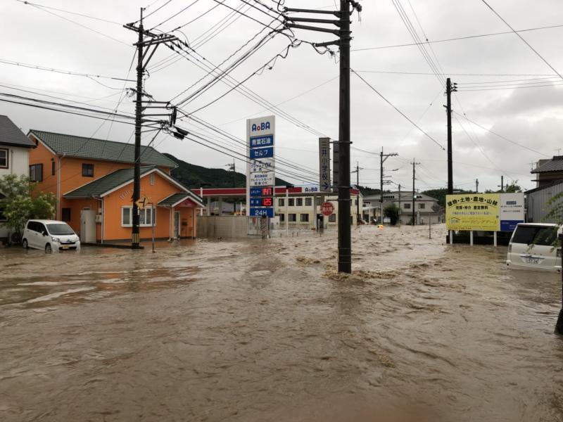 洪水で電柱や車が浸水している町の写真