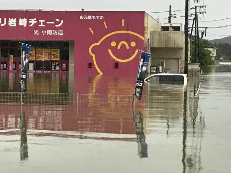 洪水により浸水したクスリ岩崎チェーンと水没した車の写真